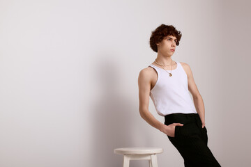 Stylish young man posing elegantly against a minimalist backdrop in a fashion forward setting