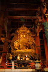 Golden Buddha Statue Inside Traditional Temple Hall With Ornate Backdrop And Wooden Ceiling. Nara City, Japan