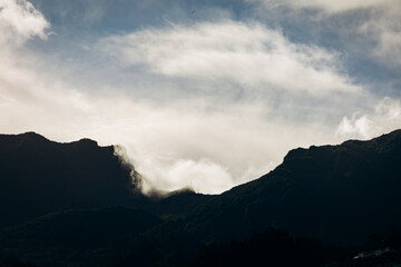 Majestic mountain silhouette under a cloudy sky, showcasing dramatic natural beauty and serene atmosphere with hints of lush greenery