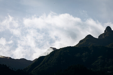 Majestic mountain peaks rise against a dramatic sky with swirling clouds, showcasing the natural beauty and tranquility of a remote landscape