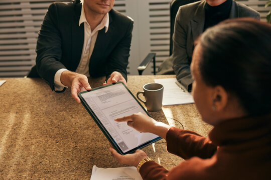 High angle view of woman filling form on digital tablet during meeting with lawyers in office