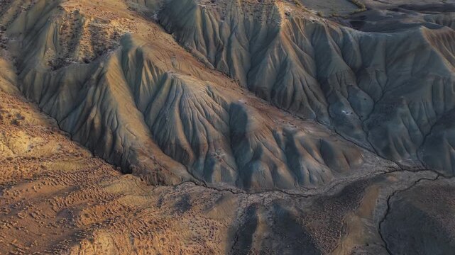 Aerial view of the rugged Calanchi del Cannizzola hills displaying a textured landscape with muted earth tones and stark shadows, Calanchi del Cannizzola, Sicilia, Italy.