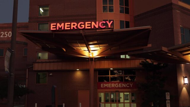Hospital Emergency Room Entrance with Red Signage. Emergency Sign at Hospital in USA. Emergency Room and Medical Care Building. Hospital, Medical Center, Emergency Room. Evening Night Times.