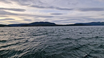 A fjord in Fauske, Norway, framed by rugged mountains and calm waters, is particularly striking in autumn. The surrounding slopes are painted in shades of gold, red, and orange as the deciduous trees 
