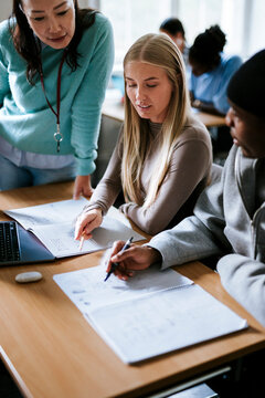 High angle view of solving math equation with assistance of female teacher in university classroom