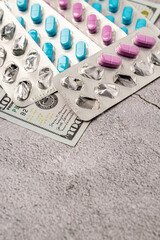 Dollar bill and a set of medicine pills. Rising costs of medical care. Reliefs for buying medicine.Pills in capsules scattered on US dollars currency.Concept of health care in USA.