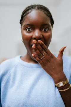 Portrait of shocked young woman with hand on mouth