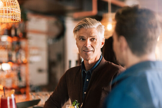Senior man talking with male friend in party at restaurant