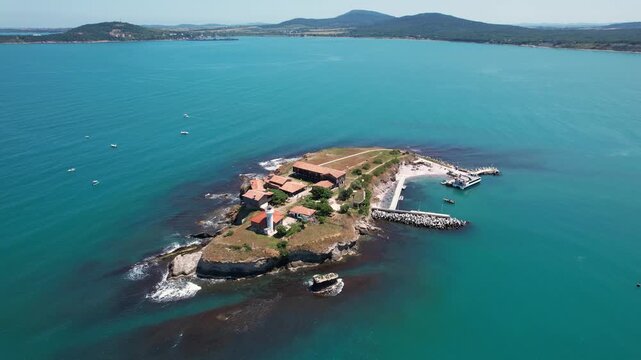 Aerial view of St. Anastasia Island with its buildings, lighthouse, and pier against the backdrop of the turquoise sea, St. Anastasia Island, Burgas, Bulgaria.