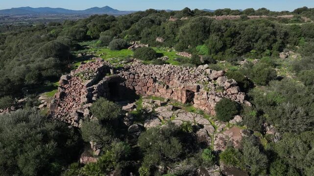 Aerial view of the ancient Nuraghe Cabu Abbas standing amidst lush greenery, its stones whispering tales of history, Olmedo, Sardinia, Italy.