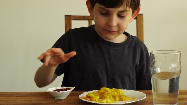 Boy eats fried potato with ketchup