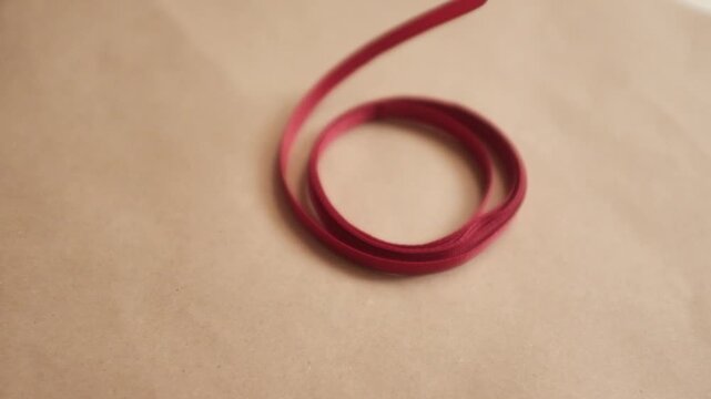 Thin red satin ribbon for wrapping presents. Unfolding a pack or ribbon. Christmas preparation. Valentines day gifts wrapping.