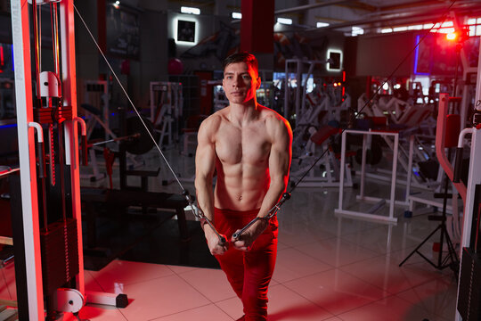 Muscular athlete performing cable crossover exercise in gym