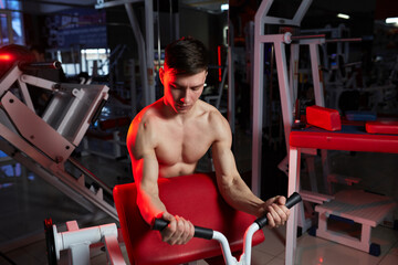 Muscular man training biceps on preacher curl machine