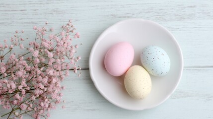 Soft pastel-colored eggs rest gently on a small plate, surrounded by delicate pink flowers. This tranquil scene evokes the spirit of Easter celebrations and joy