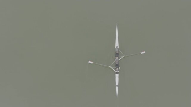 Two athletes rowing a sculling boat on calm water, teamwork and endurance in competitive sport. Practicing sport rowing. Rowers in a racing boat row in slow motion video. ProRes 422 10 bit D-Log.