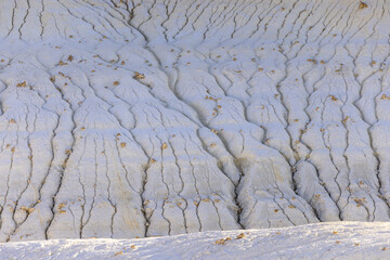 View of the stark, eroded landscape reveals intricate patterns carved into the pale earth, a testament to time and nature's artistry, Senek, Mangystau Region, Kazakhstan.