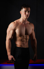 Portrait of a sweaty muscular bodybuilder posing on black background.