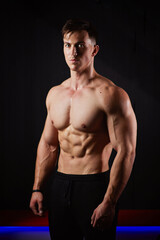Portrait of a sweaty muscular bodybuilder posing on black background.