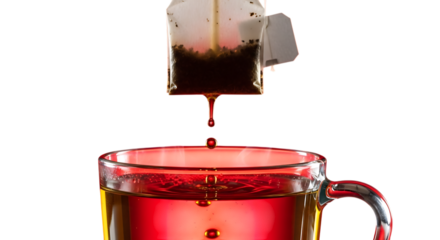 Steaming tea bag pouring into clear glass cup on black background