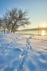 Sunny winter landscape with footprints and distant monument.
