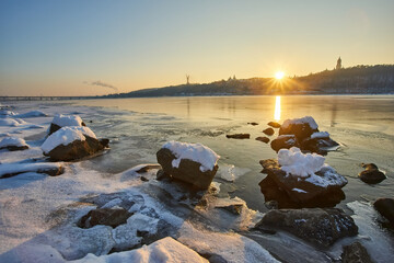 Frozen river landscape with ice chunks at golden sunset in Kyiv.