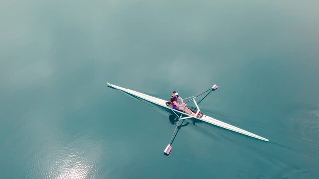 Rowing Top view of professional rower in racing boat, symbol of strength, determination and healthy active lifestyle. Single scull athlete training on water, in slow motion video 120fps.