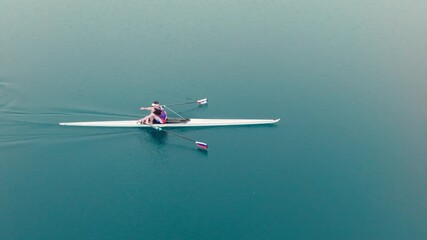 Rowing Top view of professional rower in racing boat, symbol of strength, determination and healthy active lifestyle. Single scull athlete training on water, in slow motion video 120fps.
