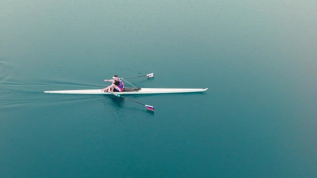 Rowing Top view of professional rower in racing boat, symbol of strength, determination and healthy active lifestyle. Single scull athlete training on water, in slow motion video 120fps.