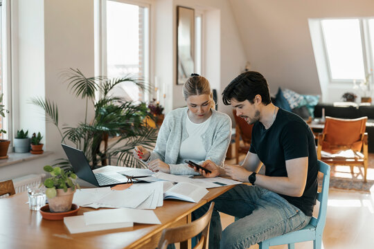 Young couple calculating savings while doing bookkeeping at home