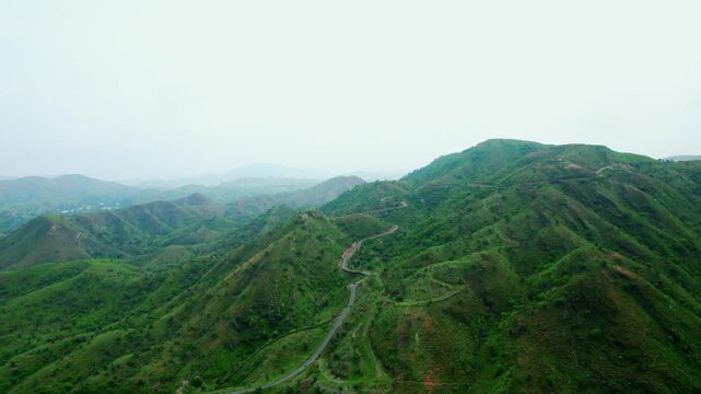 4K shot of scenic road in mountains and clouds in sky at Rayta in Udaipur, Rajasthan, India. Monsoon clouds and green hills of Rayta. Tourism and holidays background. Rayta hills in Aravalli mountain 
