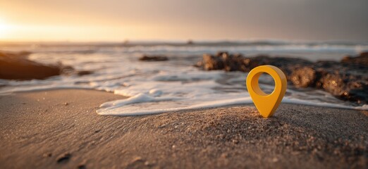 A yellow location pin on sandy shore with a blurred background of water and sky during sunset