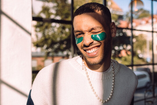 Sunlight shining on smiling man with under-eye patch winking at camera