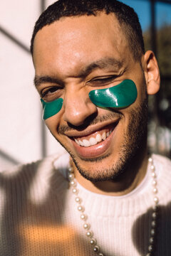 Portrait of smiling man with under-eye patch winking at camera