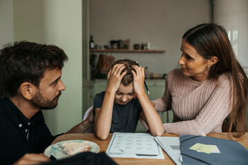 Parents consoling daughter facing difficulty over studies while doing homework at home