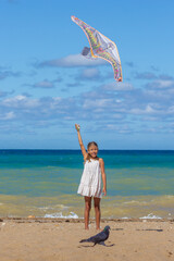 Young kid grasping a kite on the sandy shore