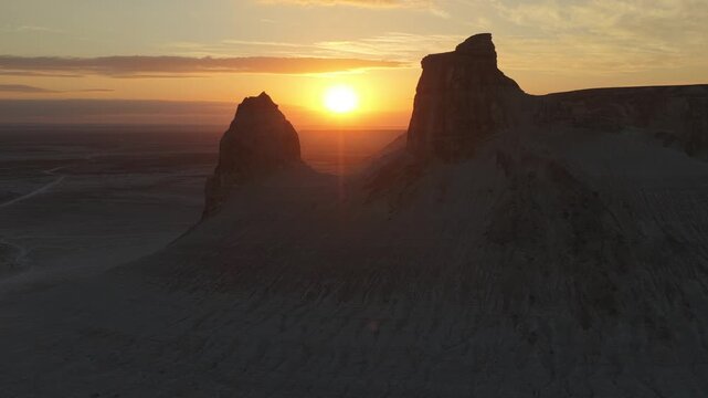 Aerial view of the sun shining on the Bozhira rock formation, creating a striking contrast of light and shadow, Bozhira, Mangystau Region, Kazakhstan.