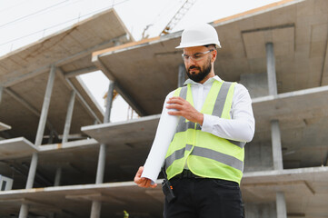 Engineer man on construction site rolling up sleeves