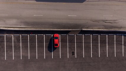 red car parked in empty lot next to road