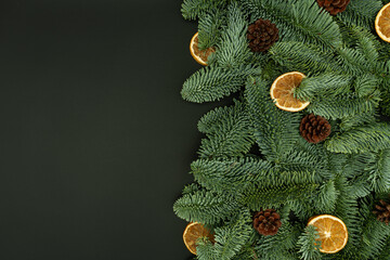 Evergreen Fir Branches with Cones and Dried Orange Slices Flat Lay on Dark Background with Copy Space