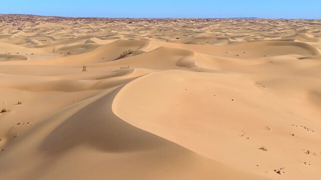 Aerial view of vast desert dunes creating mesmerizing patterns with contrasting shadows and light, showcasing the arid beauty, desert dunes Mangystau, Mangystau Region, Kazakhstan.