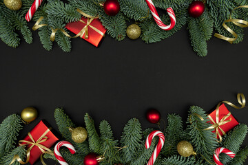Evergreen Fir Branches with Red Gift Boxes, Christmas Ornaments and Candy Canes on Dark Background with Copy Space