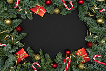 Evergreen Fir Branches with Red Gift Boxes, Christmas Ornaments and Candy Canes on Dark Background with Copy Space