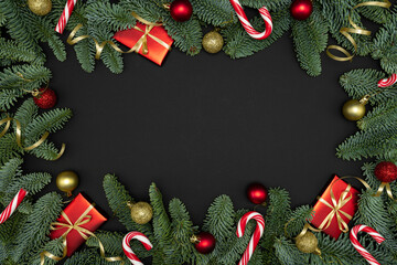 Evergreen Fir Branches with Red Gift Boxes, Christmas Ornaments and Candy Canes on Dark Background with Copy Space