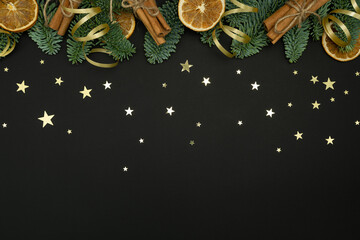 Evergreen Fir Branches with Dried Orange Slices, Cinnamon Sticks and Gold Ribbons on Dark Background with Copy Space