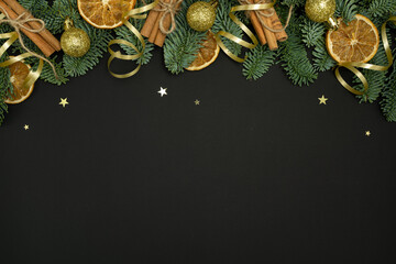 Evergreen Fir Branches with Dried Orange Slices, Cinnamon Sticks and Christmas Ornaments on Dark Background with Copy Space