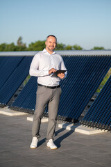 Male standing near solar panels controlling energy system