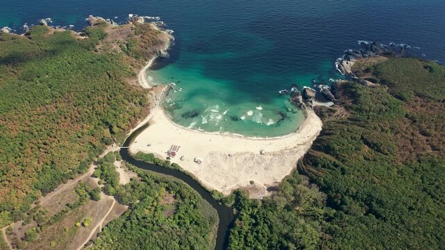 Aerial view of the golden sands of Silistar Beach meeting the turquoise  waters, framed by lush green forests and rocky cliffs, Silistar Beach,  Burgas, Bulgaria.