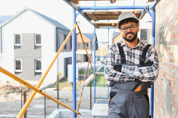 Builder posing at construction site wearing hard hat
