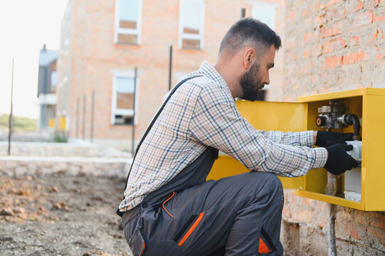 Technician installing natural gas meter on residential building